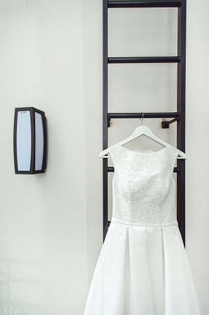gorgeous white wedding dress on a fire ladder at the balcony. brides accessories in a wedding dayの写真素材