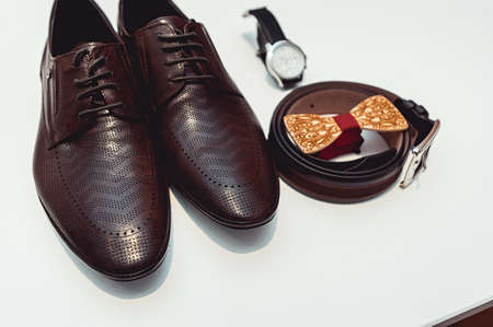 Wooden bow tie, brown leather shoes, belt, watch. Grooms wedding morning. Close up of modern man accessoriesの写真素材