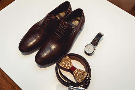 Wooden bow tie, brown leather shoes, belt, watch. Grooms wedding morning. Close up of modern man accessoriesの写真素材