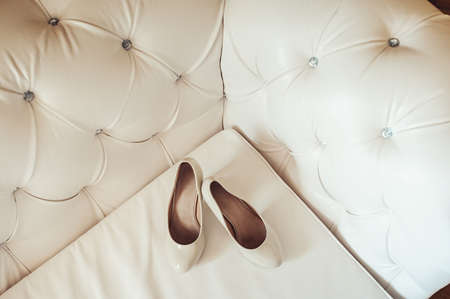 brides biege shoes on heel on a leather vintage sofaの写真素材