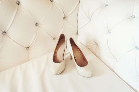 brides biege shoes on heel on a leather vintage sofaの写真素材