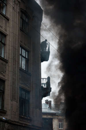 fire during urban riots, a lot of smoke. Protester watching from the balcony of the fireの写真素材