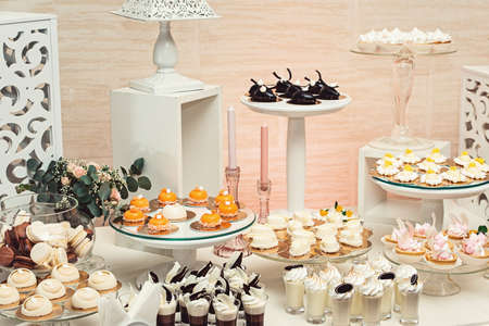modern stylish luxury wedding candy bar. a wide range of sweets. chocolate, white, orange sweets on gilded paper on the white table. glass standsの写真素材