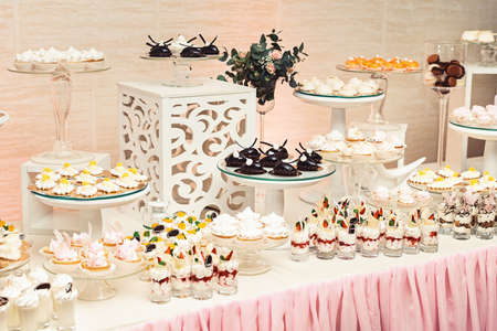 modern stylish luxury wedding candy bar. a wide range of sweets. chocolate, white, orange sweets on gilded paper on the white table. glass standsの写真素材