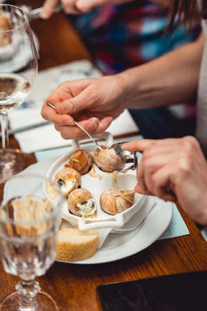 Snails with herbs butter, in traditional ceramic pan bread and sauce on a rustic wooden table. Top...