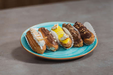 Eclairs with different ganache and icing with different toppings on a plate