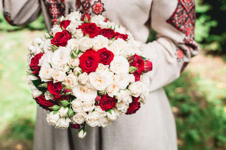 bride hold in hand wedding bouquet of biege and red roses.Wedding dayの写真素材