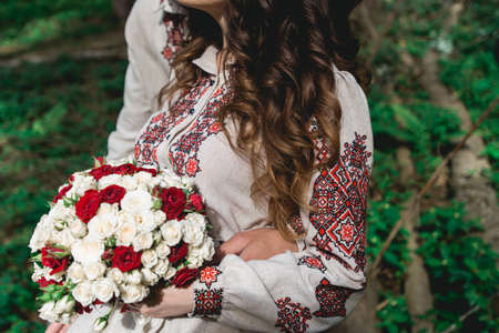 bride hold in hand wedding bouquet of biege and red roses.の写真素材