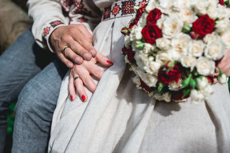 fiance and the bride hold in hand wedding bouquet of biege and red roses.の写真素材