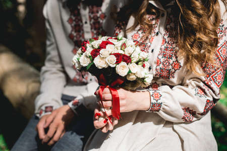 fiance and the bride hold in hand wedding bouquet of biege and red roses.の写真素材