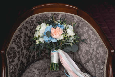 luxurious wedding bouquet made of roses, carnation and hydrangea on a vintage chairの写真素材