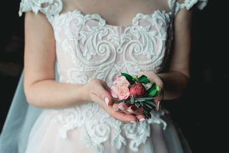 bride in a luxurious wedding dress holding a wedding buttonhole made of rosesの写真素材