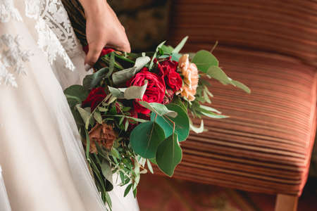 bride in a luxurious wedding dress with lace in the chutch holding a wedding bouquet made of rosesの写真素材