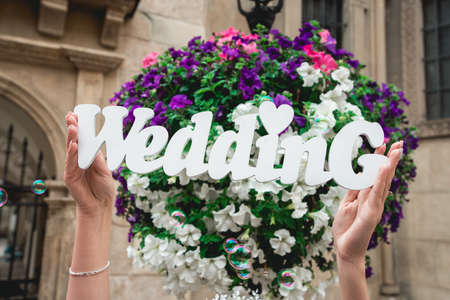 womens hands with the word of wedding on the background of flowers and soap bubblesの写真素材