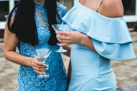 girls in blue dresses with glasses of alcohol in their hands at the party.の写真素材