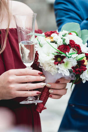 Girl in a pomegranate dress and with red manicure holding in her hands glass with champagneの写真素材