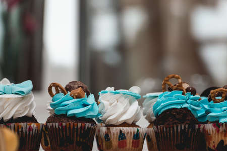 rows of birthday cupcake with butter white and blue cream icing on a glass standの写真素材
