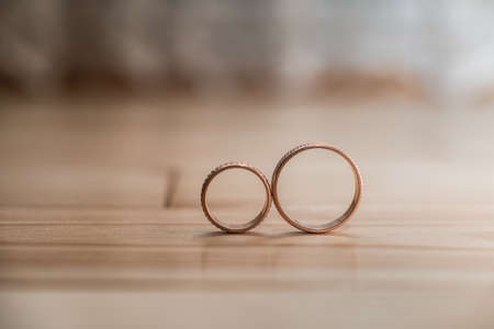 Pair of wedding golden rings on the yellow wooden floorの写真素材