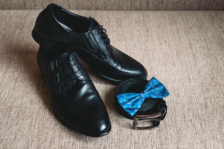 Blue bow tie, leather black shoes and belt. Grooms wedding morning. Close up of modern man accessoriesの写真素材