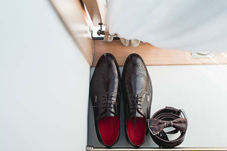 Brown bow tie lies on a belt, leather shoes. Grooms wedding morningの写真素材