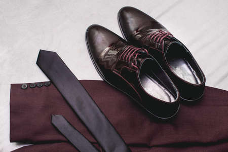 Suit, necktie, leather shoes on a white textile. Grooms wedding morning. Close up of modern man accessoriesの写真素材