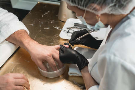 First steps. Cropped shot of a salon client holding her hand in a bowl of water preparing for the manicureの写真素材