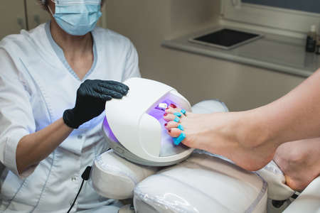Pedicure foot and nails treatment with cosmetic products and UV lampの写真素材
