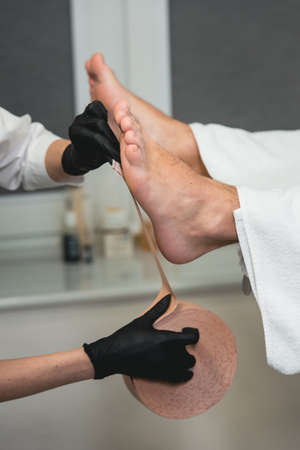 Therapeutic treatment of leg with beige physio tapeの写真素材