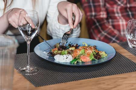 woman eats delicious salmon salad with egg in a restaurant. small portionの写真素材