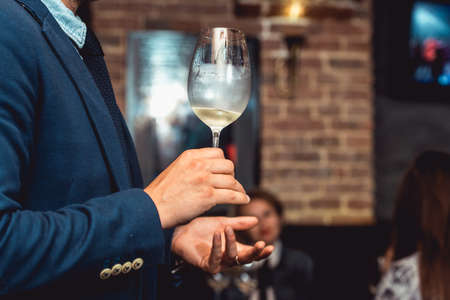 man in a blue suit holds glass of white wineの写真素材