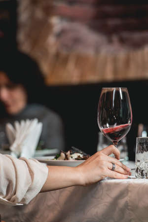woman holds glass of red wine. people consider the color of the wine and try how it smells in different glassesの写真素材