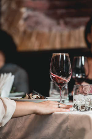 woman holds glass of red wine. people consider the color of the wine and try how it smells in different glassesの写真素材