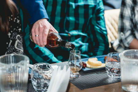 sommelier pouring whiskey into glass at hard alcohol tastingの写真素材