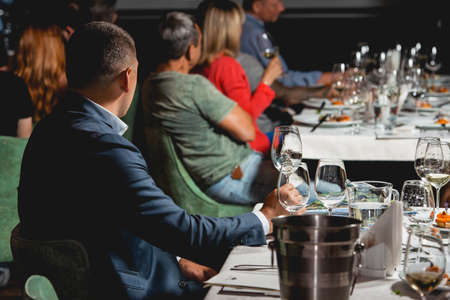 People seats at the Served table for food and wine tasting. Snacks with shrimp, fish fillets, Spain...