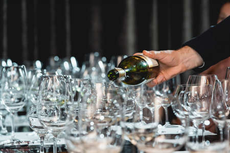 sommelier pouring white wine into glass at wine tasting
