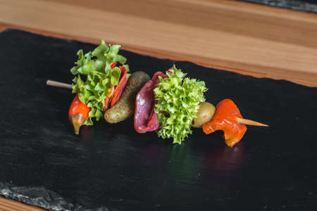spanish snack, banderillas on skewers with salami, pickling olives, pickles, green and red pepper