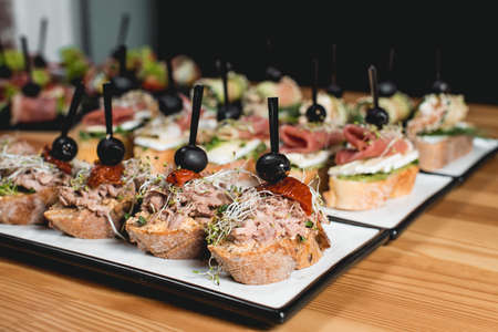 tasty pinchos with tuna, chorizos, salmon, egg, dried tomatoes, avocado, salmon, bacon, Hamon, Brie Cheese, Olives and Pesto Sauce, traditional spanish snackの写真素材