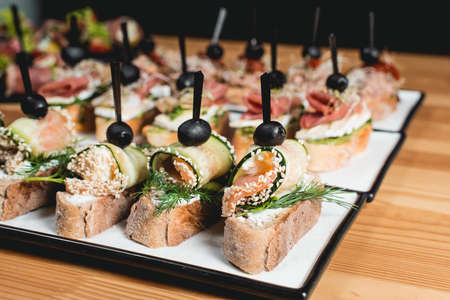 tasty pinchos with tuna, chorizos, salmon, egg, dried tomatoes, avocado, salmon, bacon, Hamon, Brie Cheese, Olives and Pesto Sauce, traditional spanish snackの写真素材
