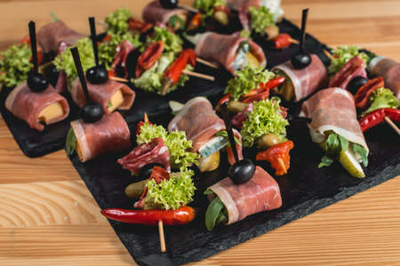 spanish snack, banderillas on skewers with jamon, ramses, pear, dorblue, chorizo, dried tomato, champignon, pickling olives, garlic, pickles, gouda, green, onion and red pepperの写真素材