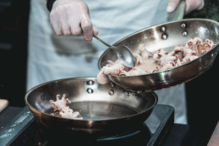 The chef cooks the small octopus on a metal frying panの写真素材