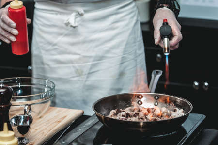The chef cooks the small octopus on a metal frying panの写真素材