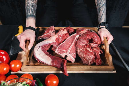 raw meat different kinds . Meat board in the hands of the chef. Cook offers steaks to choose from. Close-up in the kitchenの写真素材