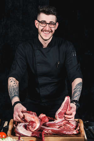 raw meat different kinds . Meat board in the hands of the smiling chef offers steaks to choose from. Close-up in the kitchenの写真素材