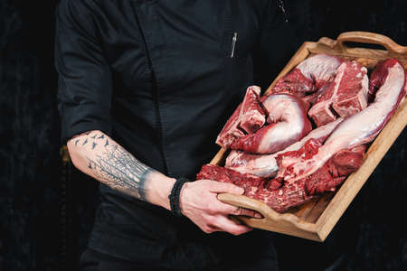 raw meat different kinds . Meat board in the hands of the chef. Cook offers steaks to choose from. Close-up in the kitchenの写真素材