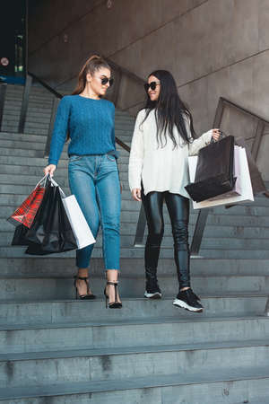 Beautiful girls with paper bags outside shopping mallの写真素材