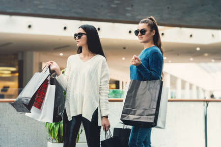 Beautiful girls with paper bags in a hall of a shopping mall