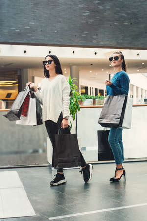 Beautiful girls with paper bags in a hall of a shopping mallの写真素材