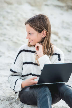 11 years girl with tablet pc in hsnds. against a sand hill. close upの写真素材