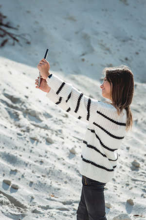 11 years girl with tablet pc making selphie against a sand hill. close upの写真素材