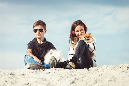 Happy 11 year old boy hugging his dog breed Samoyed at the seashore against a blue sky close up. Best friends rest and have fun on vacation, play in the sandの写真素材